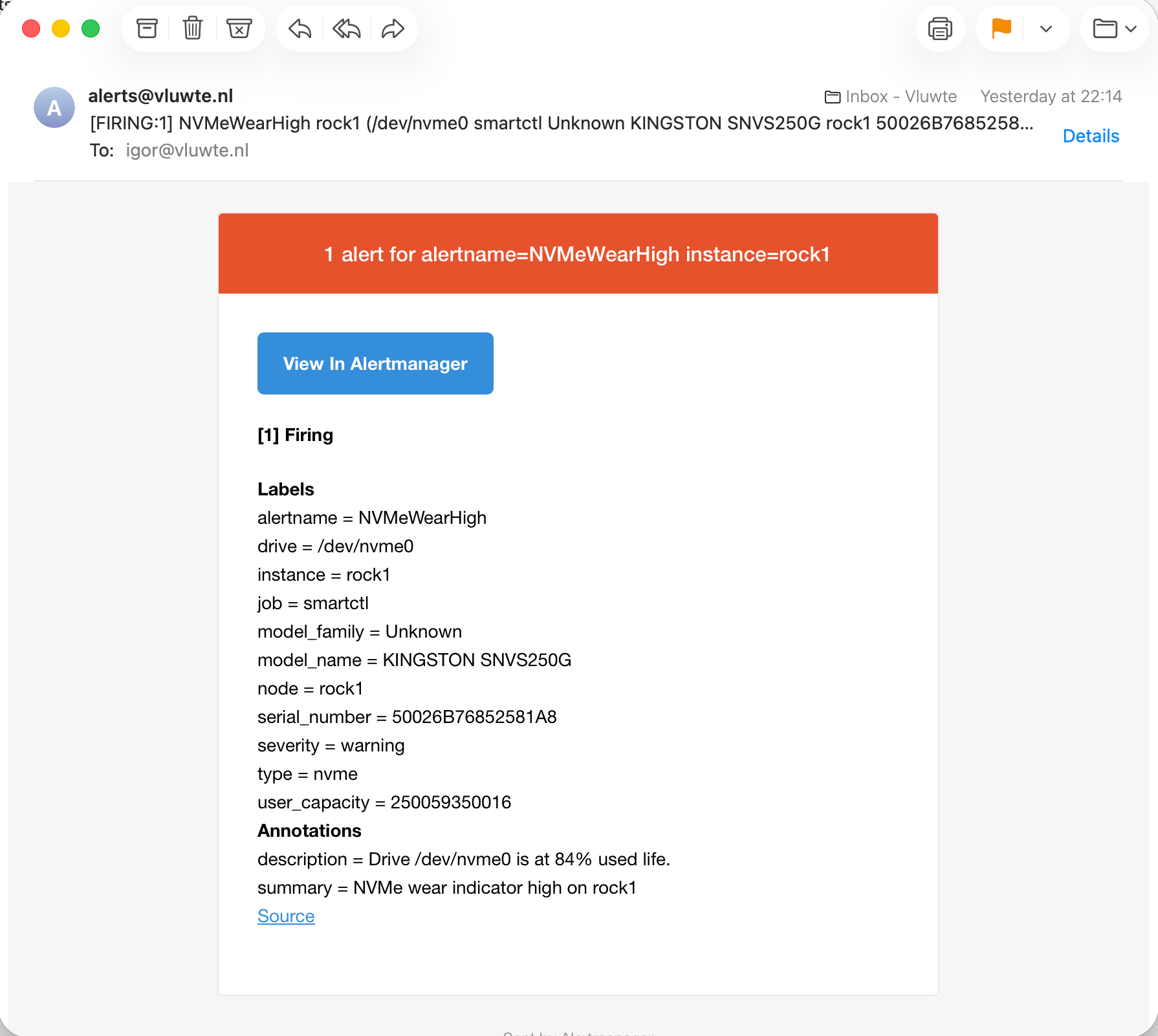 Alertmanager email from alerts@vluwte.nl received at 22:14 with subject "[FIRING:1] NVMeWearHigh rock1 (/dev/nvme0 smartctl Unknown KINGSTON SNVS250G rock1 50026B7685258…". The red header reads "1 alert for alertname=NVMeWearHigh instance=rock1". The body lists labels alertname NVMeWearHigh, drive /dev/nvme0, instance rock1, job smartctl, model_family Unknown, model_name KINGSTON SNVS250G, node rock1, serial_number 50026B76852581A8, severity warning, type nvme and user_capacity 250059350016, with the description "Drive /dev/nvme0 is at 84% used life." and the summary "NVMe wear indicator high on rock1".